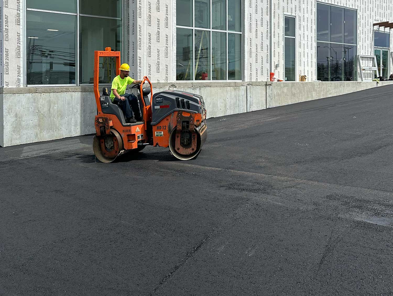 Parking lot paving project showing asphalt being installed and compacted
