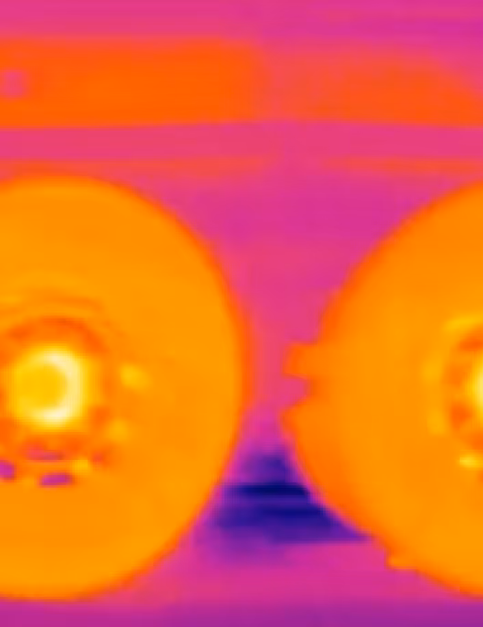 Thermal image showing two bright orange heated wheel hubs against a cooler purple background.