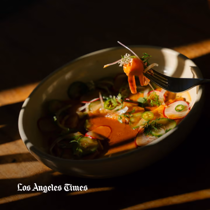 Vibrant ceviche bowl with salmon, radish, cucumber, jalapeño, and cilantro lifted on a fork, featured in Los Angeles Times.