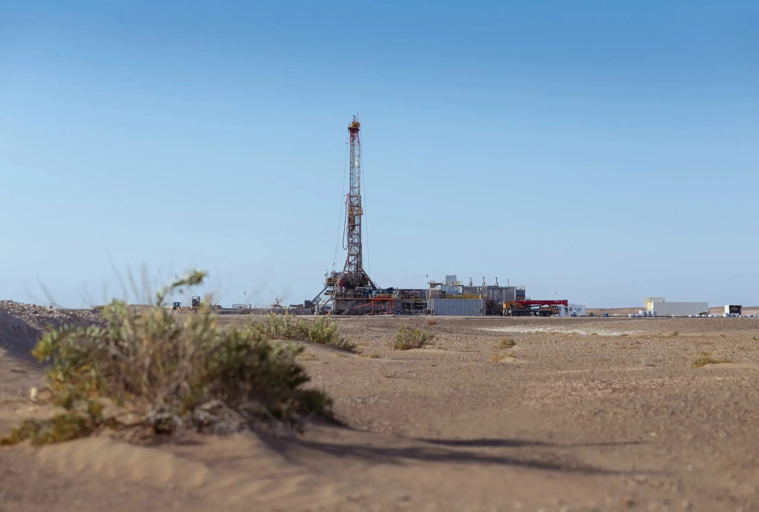 Drilling rig on the desert horizon beyond native scrub