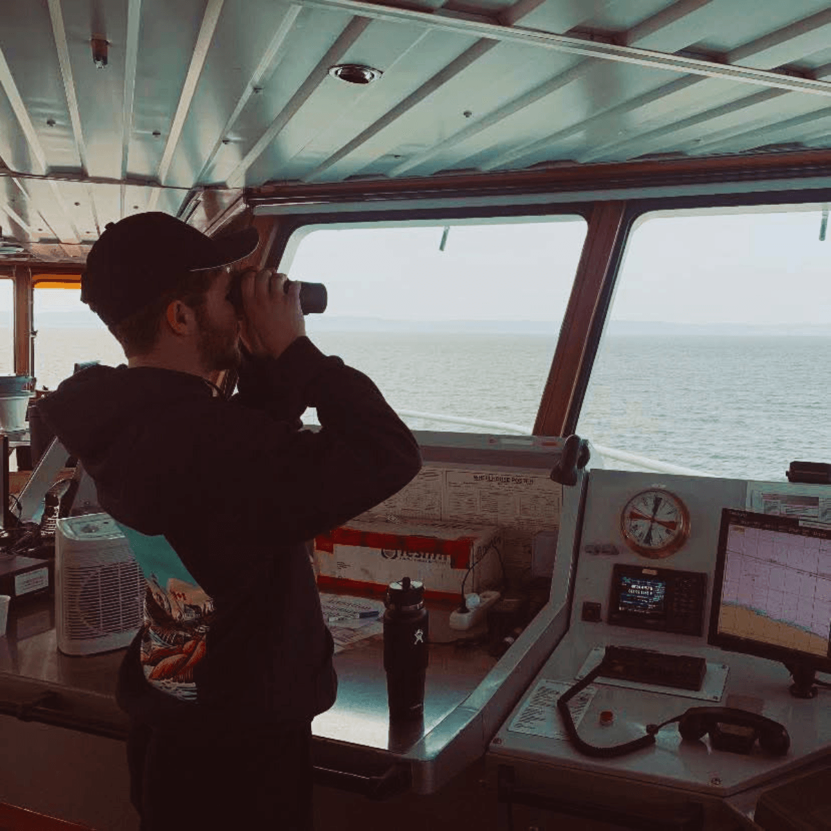 Homme sur un bateau qui regarde la mer avec des jumelles