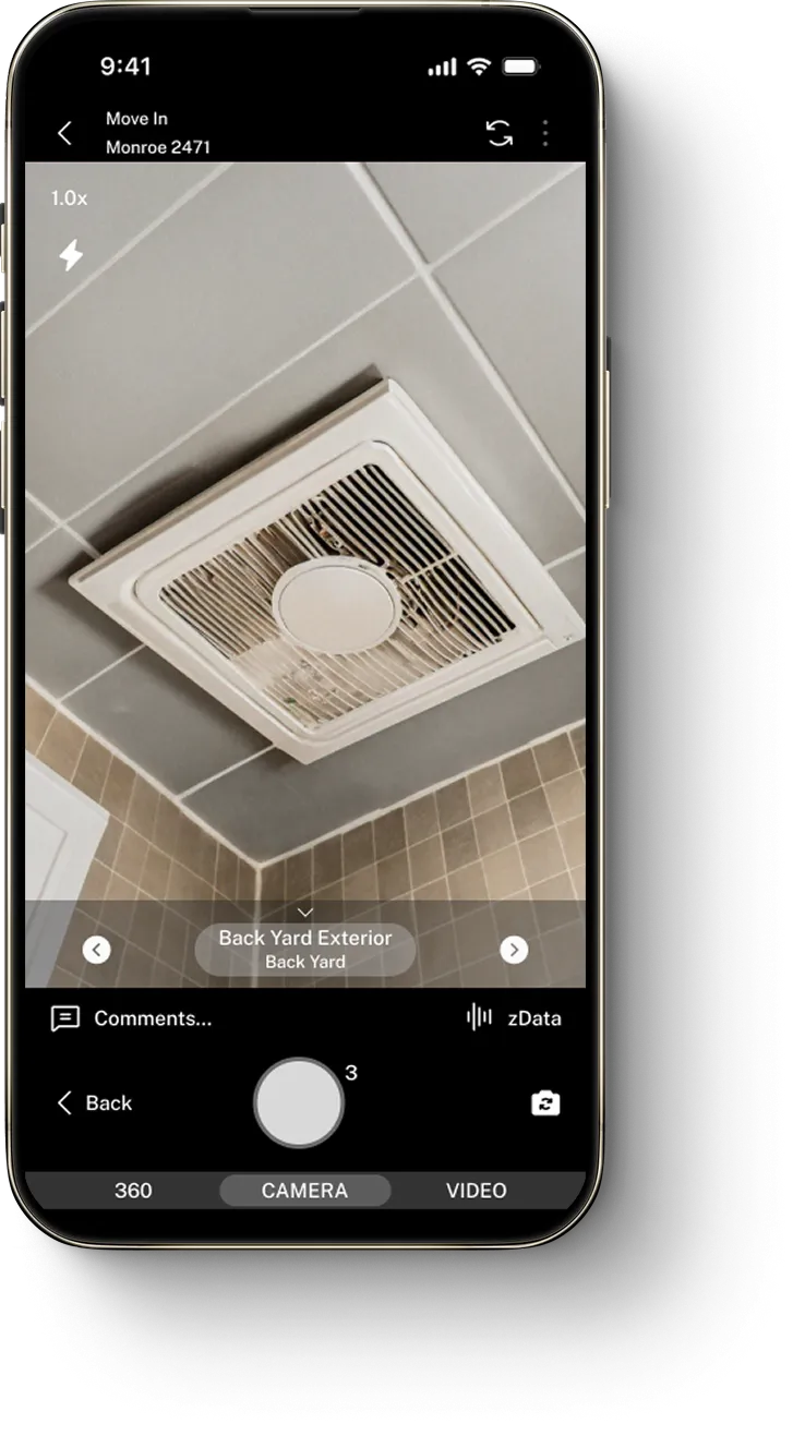Smartphone screen shows a ceiling exhaust fan in a tiled bathroom on a camera app interface.
