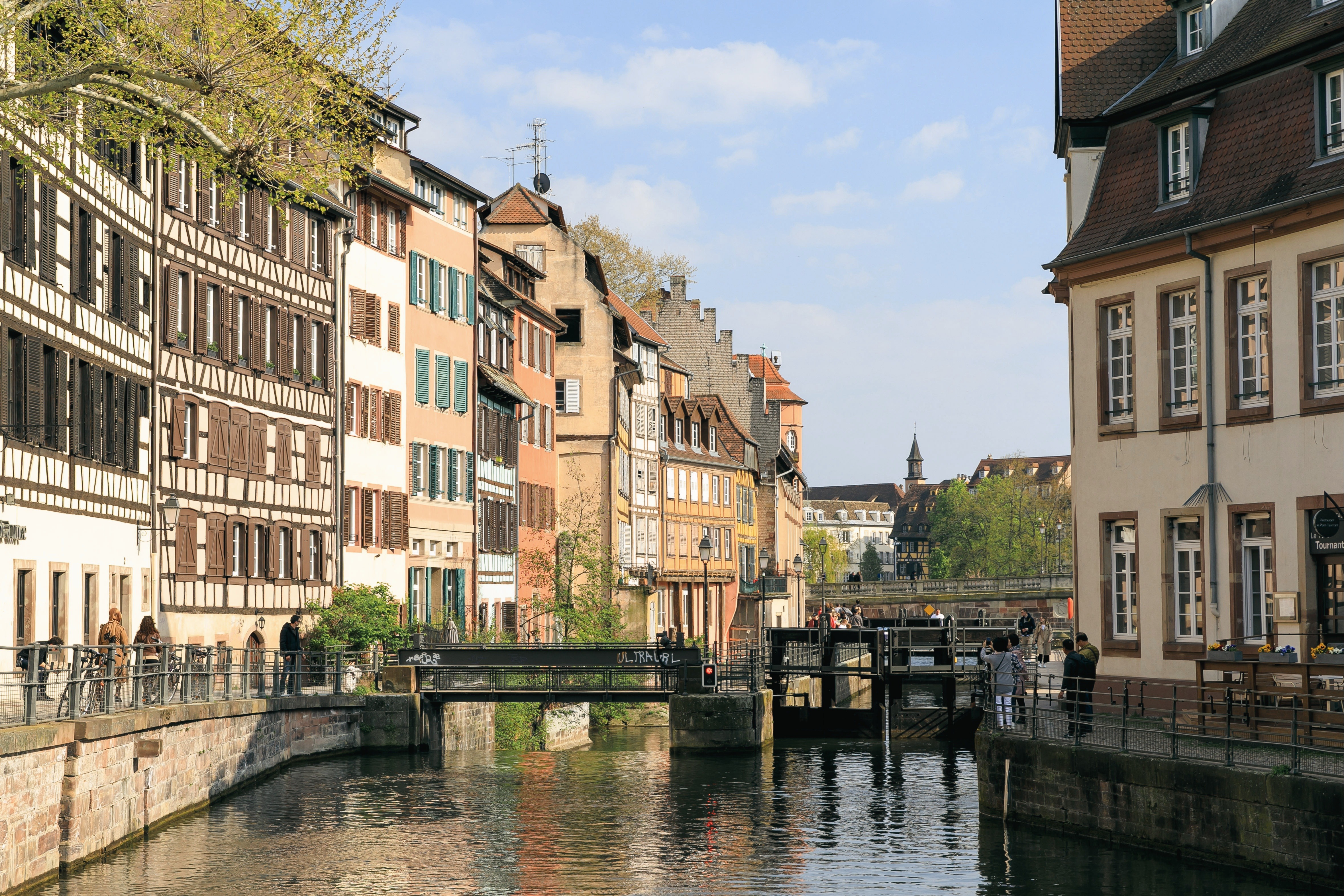Vieilles maisons colorées le long d'un canal avec pont et passants à Strasbourg