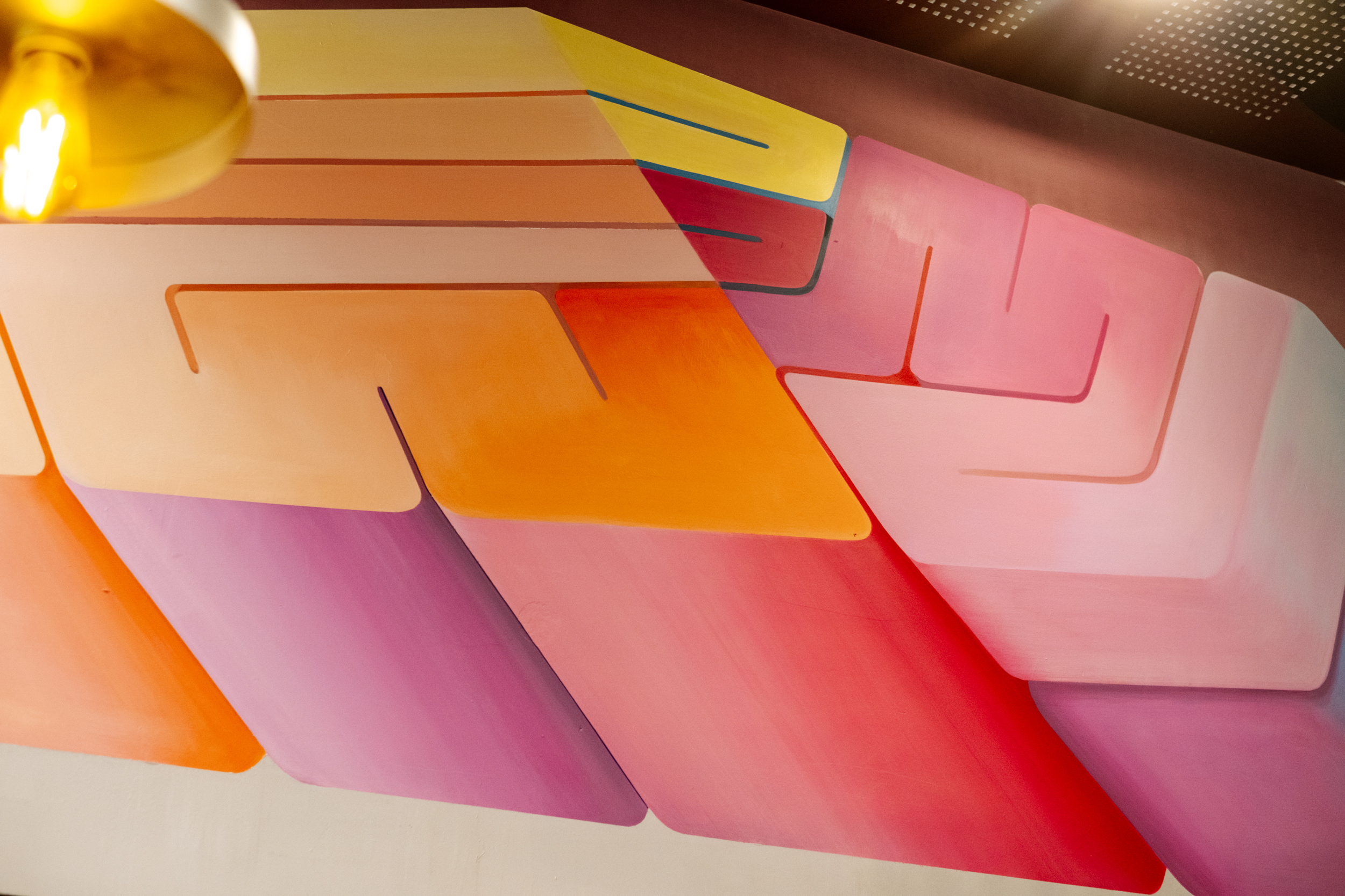 Peinture murale abstraite colorée avec formes géométriques orange, rose, violet et jaune.