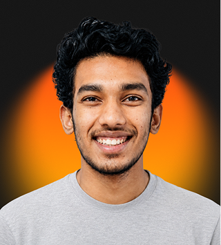 Smiling young man with curly hair wearing a light gray shirt on a black and orange background.