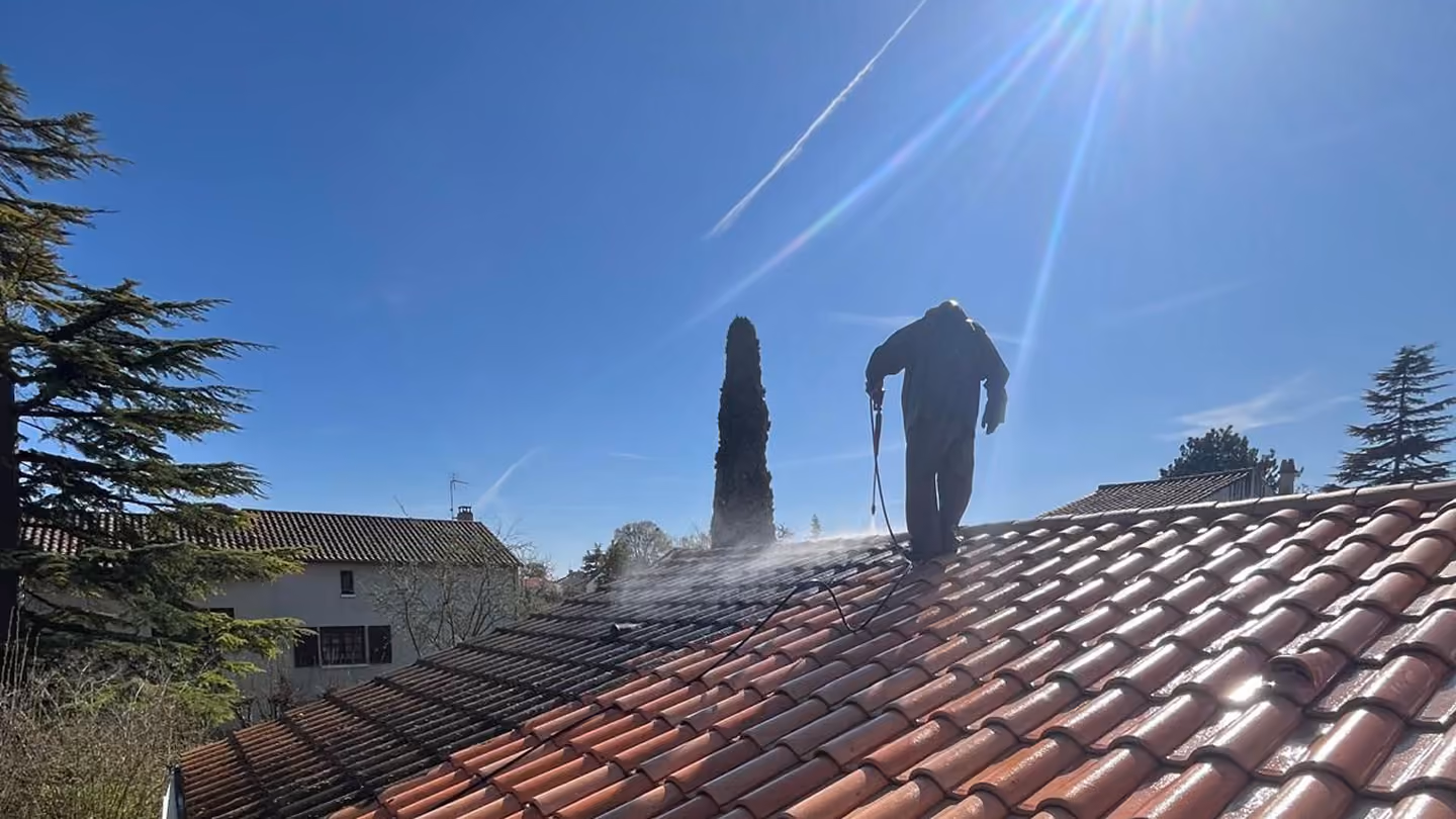 Deux couvreurs interviennent sur une toiture en tuiles.