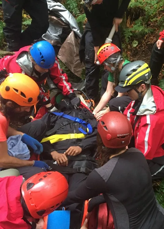 Smiling course participant wearing a helmet with a camera during outdoor rescue training