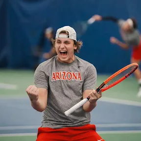 herman hoey, an excited tennis player in Arizona shirt celebrating with clenched fists on indoor court.