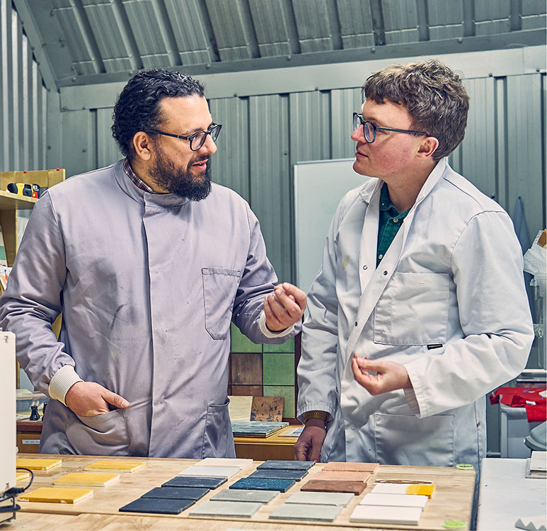 Dr Aled Roberts, CEO, and
Dr Periklis Petropoulos, Senior Engineer, in discussion in a lab, overlooking an array of coloured sustainable Eralith tiles.
