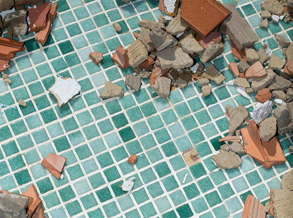 A composition of blue and green Eralith tiles, with crumbled bricks and building materials lying on top. 