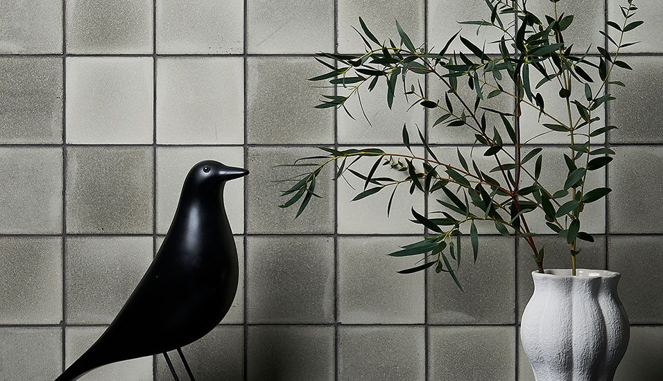 An internal wall decorated with grey Eralith tiles, with household furnishings in front. 