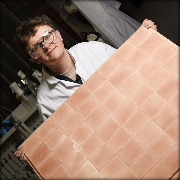 CEO Dr Aled Roberts displaying a large compilation of light-orange sustainable Eralith tiles. 