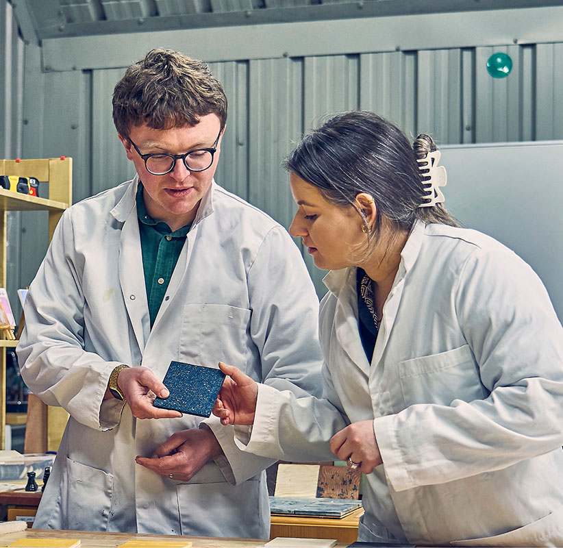 CEO Dr Aled Roberts and a scientist examining a blue Eralith tile in a lab.