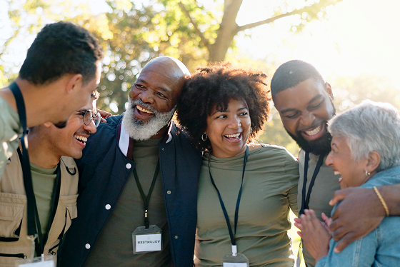 Group of diverse faith-based church donors smiling and talking outdoors, wearing badges and casual clothes.