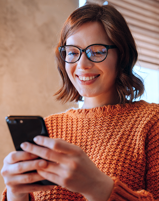 Female church donor wearing glasses and an orange sweater using a mobile phone to give to her church.