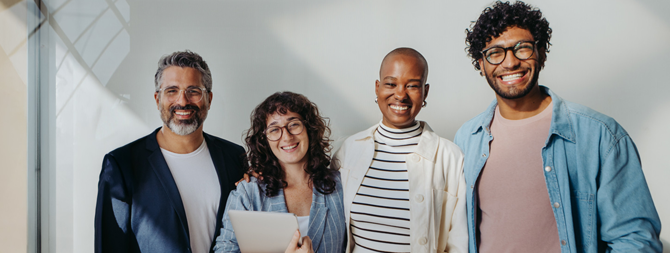 Group of people standing close together smiling in casual attire, holding a tablet, representing the four different faith-based donor profiles
