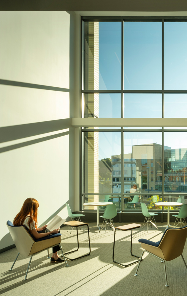 A person working in a large office with high windows.