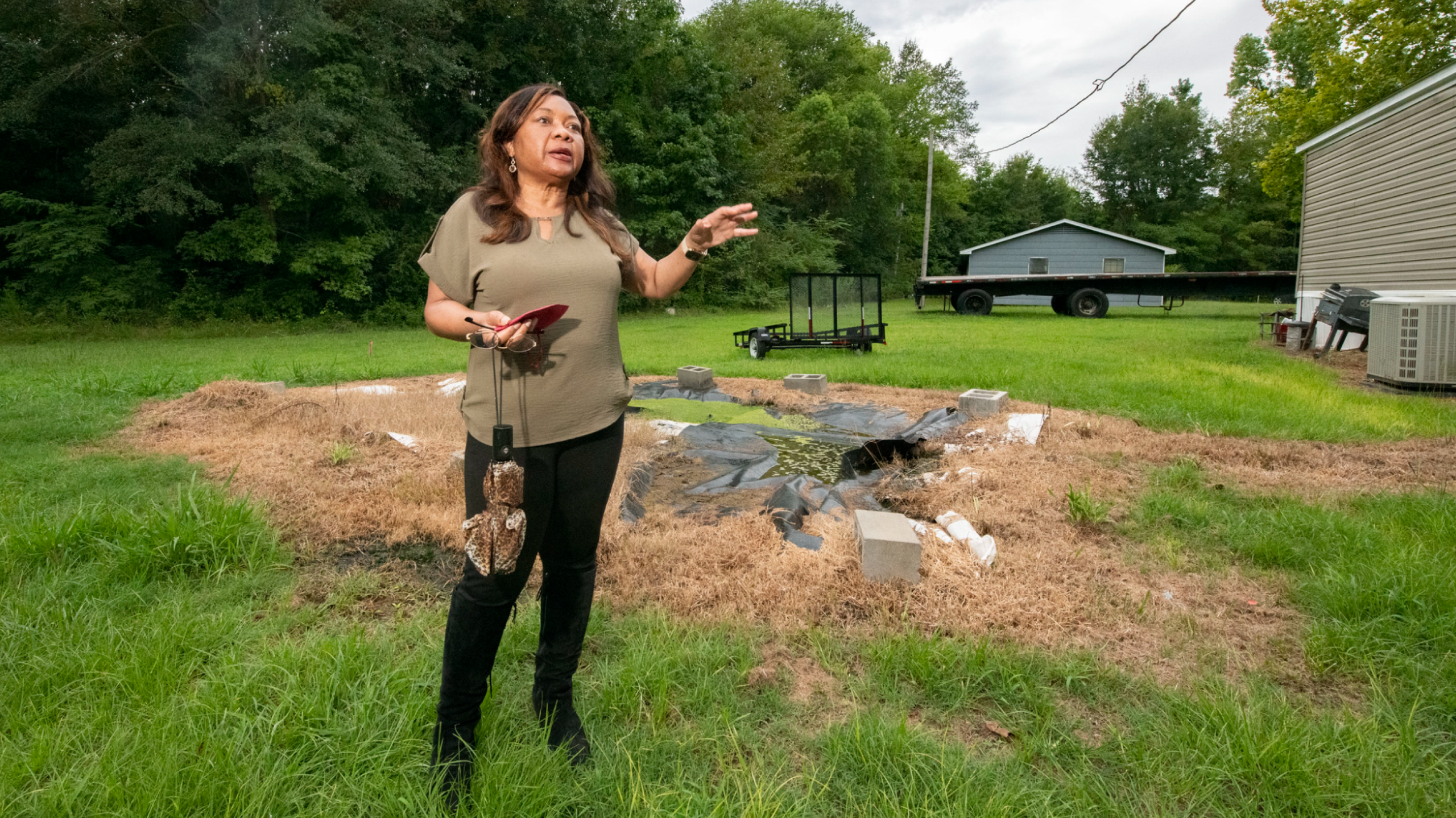 Catherine Coleman Flowers standing in front of a failed sewage disposal system in a yard in rural Alabama. 