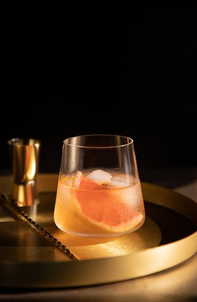 Drink with orange and ice on the golden plate