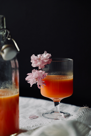 Grapefruit juice with flowers on white table