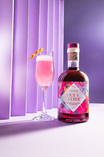 Botle and glass of Viola Verde drink with purple background