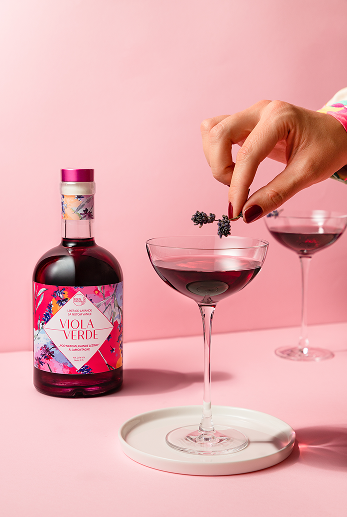 Two glasses and botle of Viola Verde drink and girls hand with purpple flower
