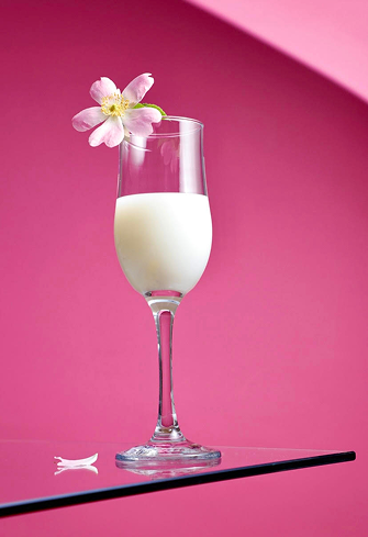 A glass of white wild rose drink with a flower