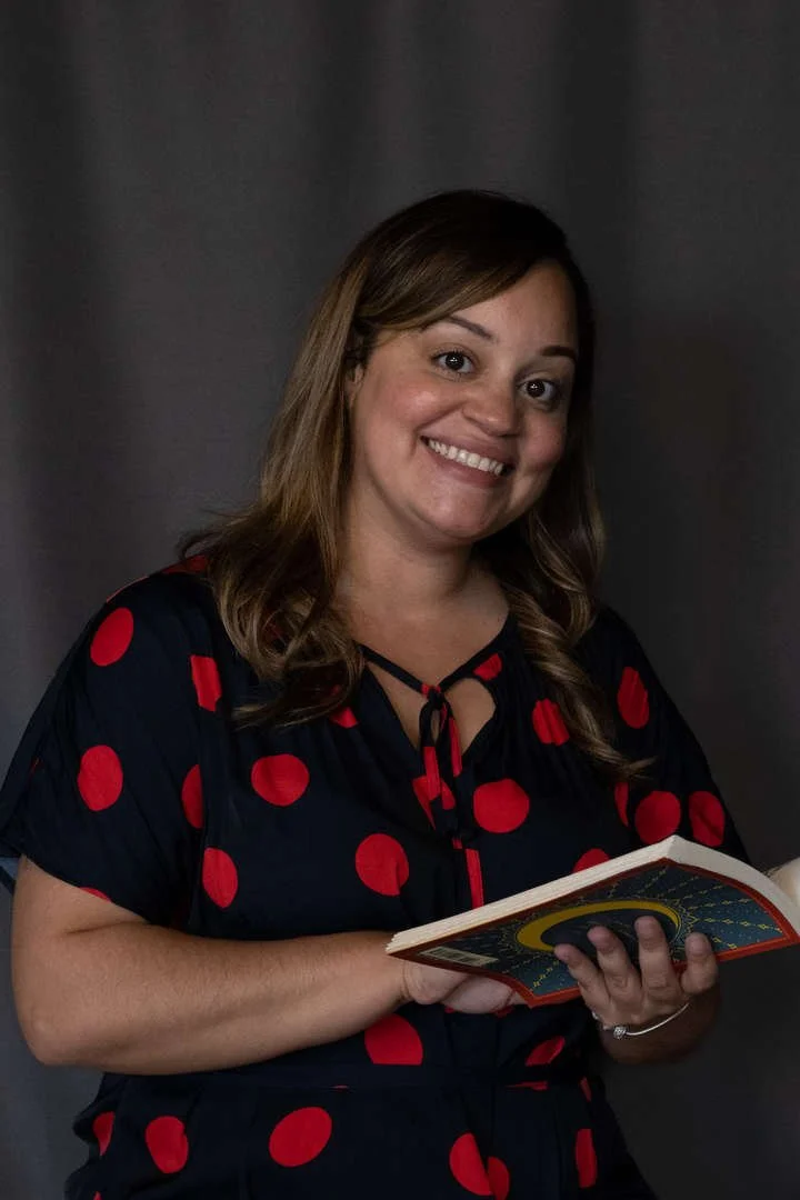 Staff member D. Concepcion smiling and holding a book