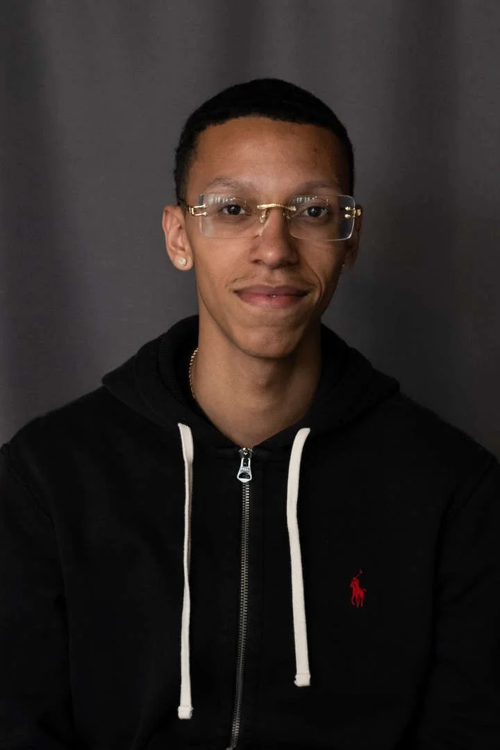 B Rivera staff portrait smiling in black hoodie with glasses