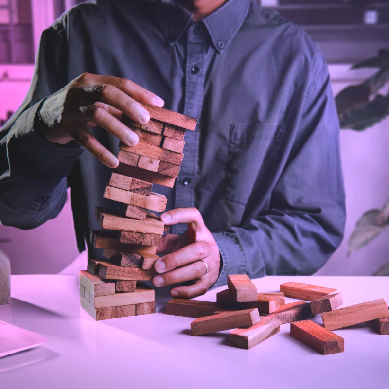 Person stapelt Holzklötze als Symbol für Strategie, Fundament und Themenklarheit im LinkedIn-Marketing.
