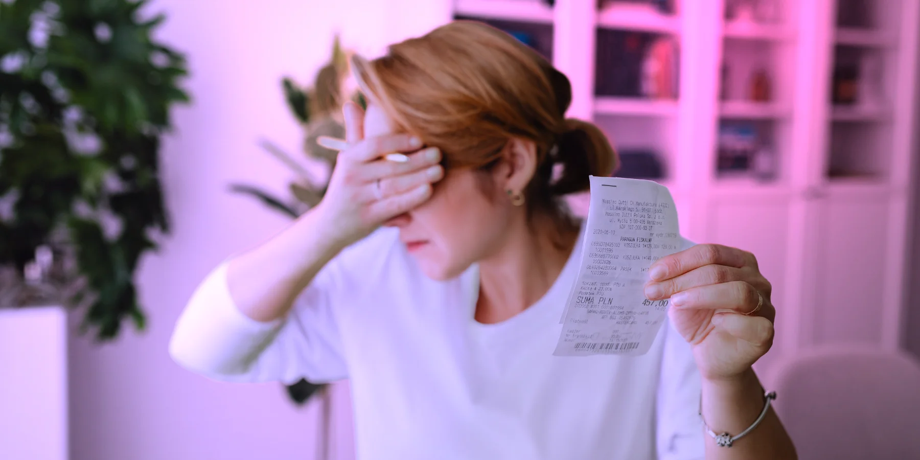 Person hält eine Quittung in der Hand und verdeckt das Gesicht. Symbolbild für unerwartete Kosten durch versteckte Gemini Thinking Tokens.
