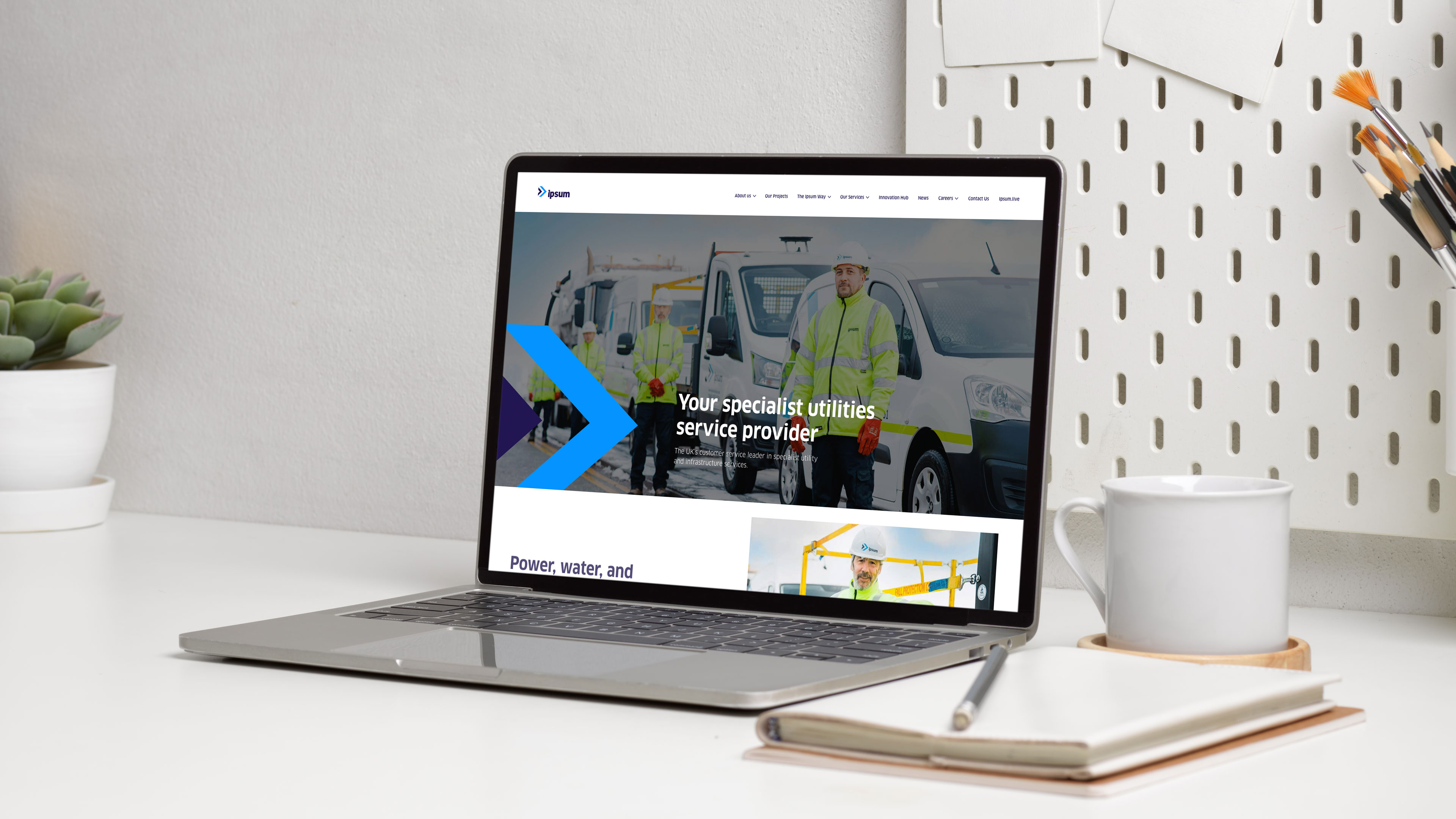 Laptop on a white desk displaying a utilities service provider website with workers in high-visibility jackets and vans.