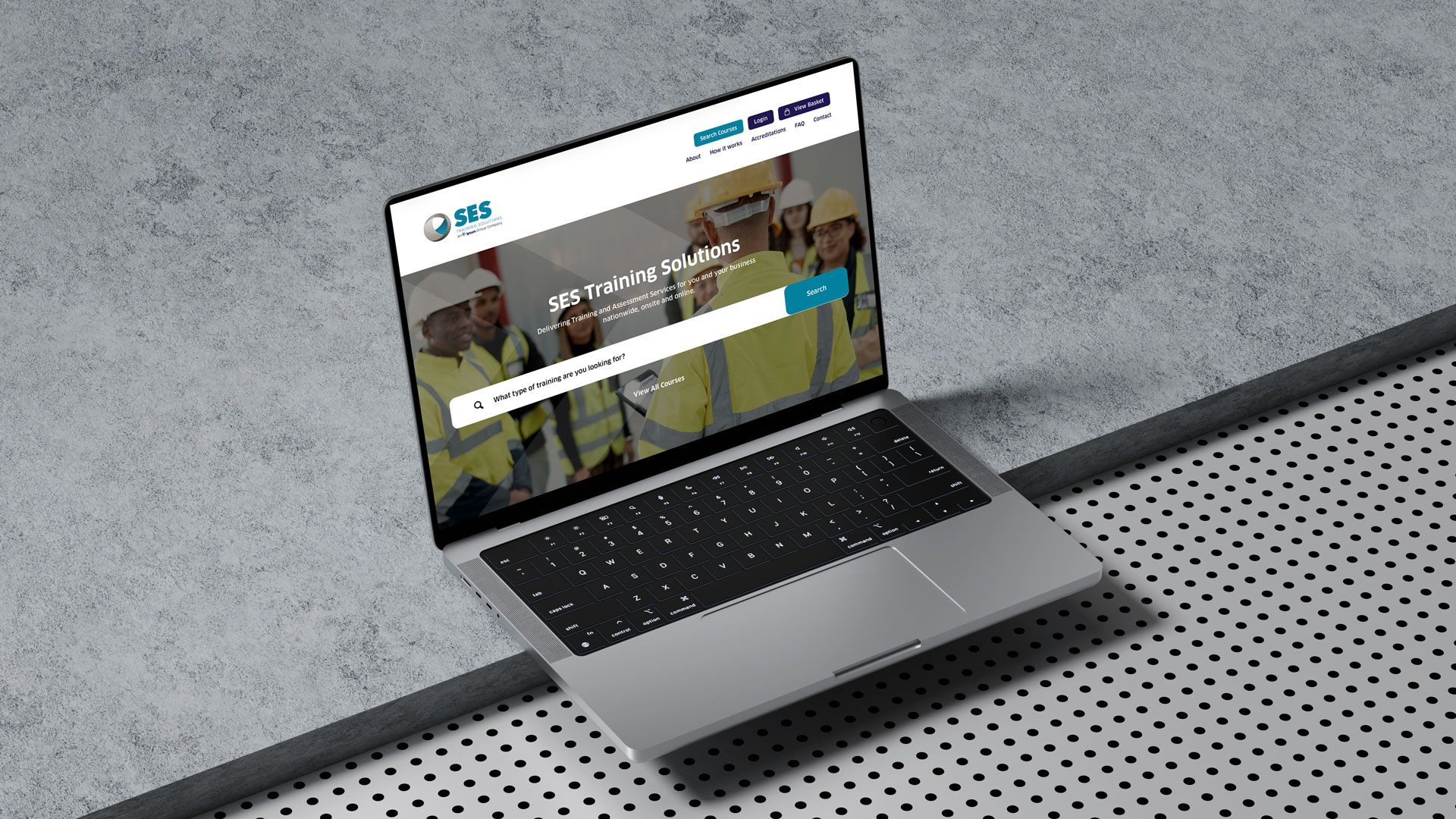 Open laptop displaying SES Training Solutions website with search bar and workers in yellow safety vests and helmets in background.