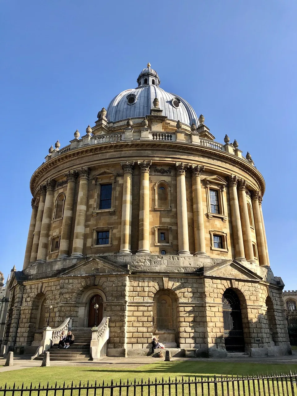 Radcliffe Camera, a circular neoclassical building with large columns and a domed roof, under a clear blue sky in Oxford.