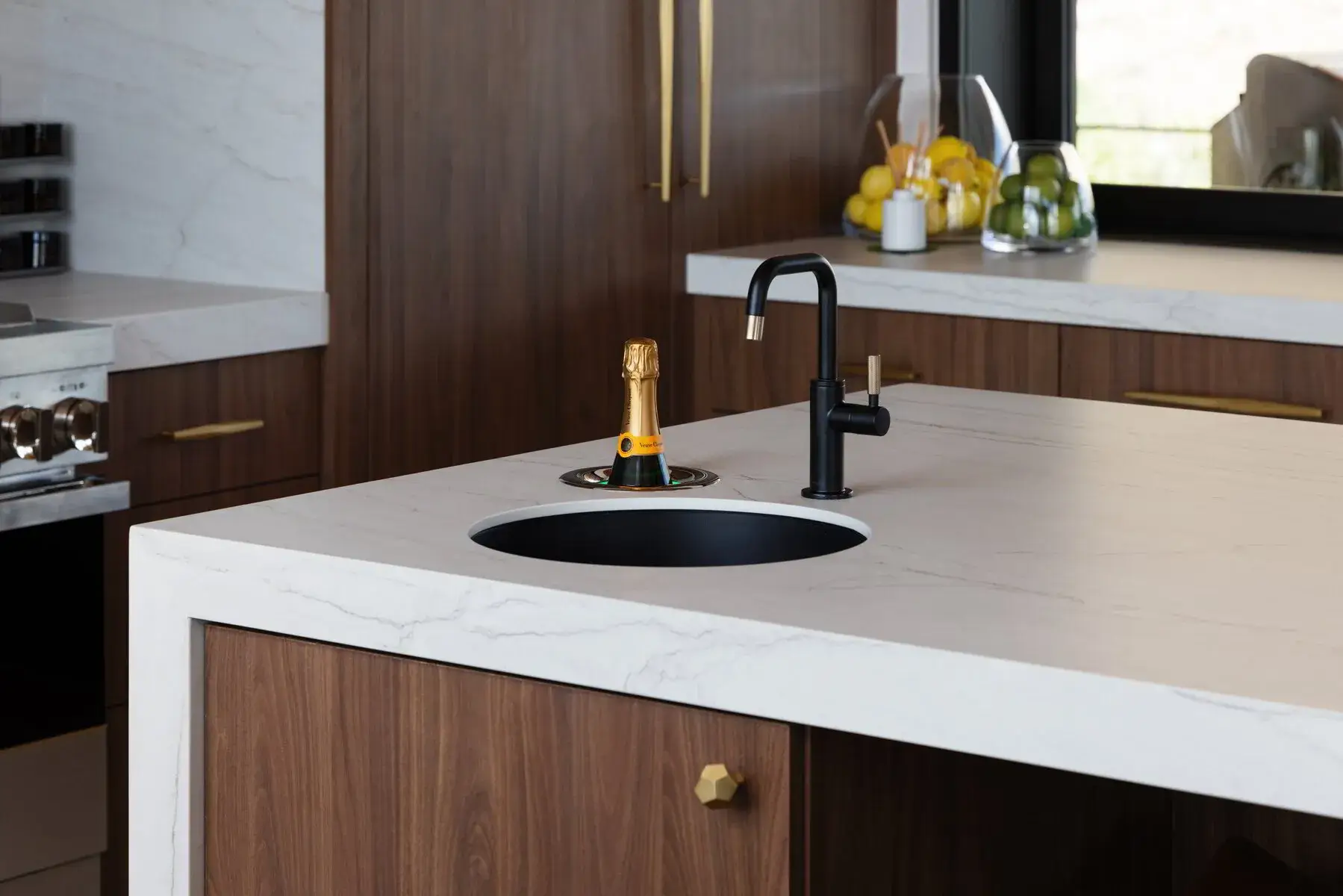 Modern kitchen island with white marble countertop, black sink and faucet, and a champagne bottle cooler.