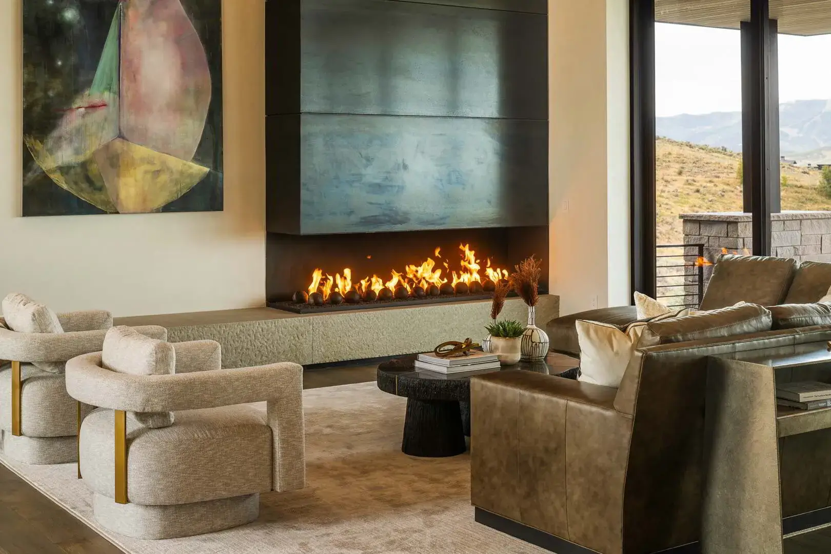 Modern living room with brown leather sofa, beige armchairs, black coffee table, and lit fireplace.