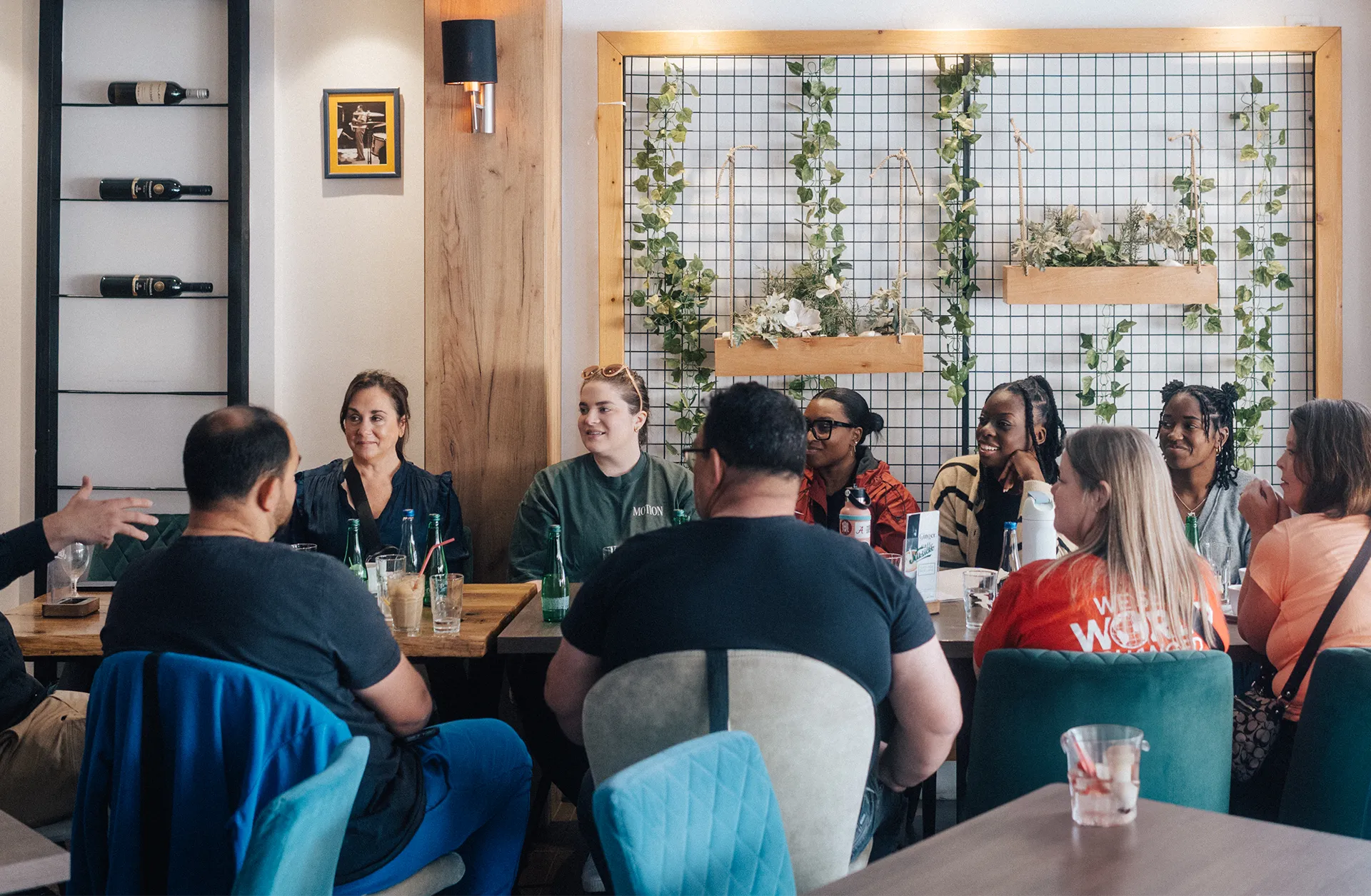 A diverse group of people sitting around a table in a cozy restaurant, engaged in conversation and smiling.