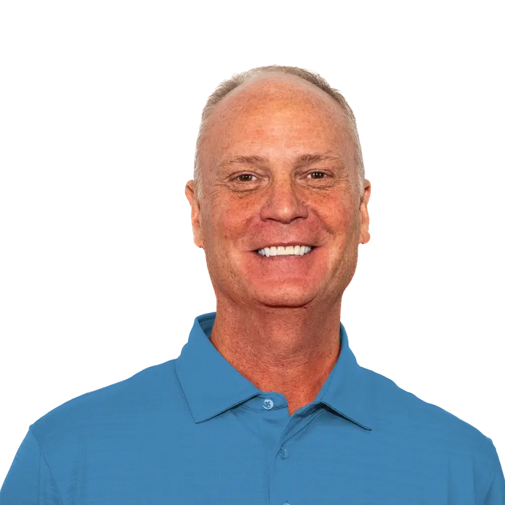Smiling middle-aged man with short hair wearing a blue polo shirt with a small embroidered animal logo.