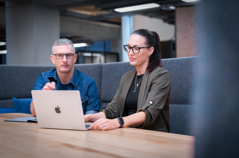Two PDC Creative team members reviewing marketing plans on a laptop together in the office