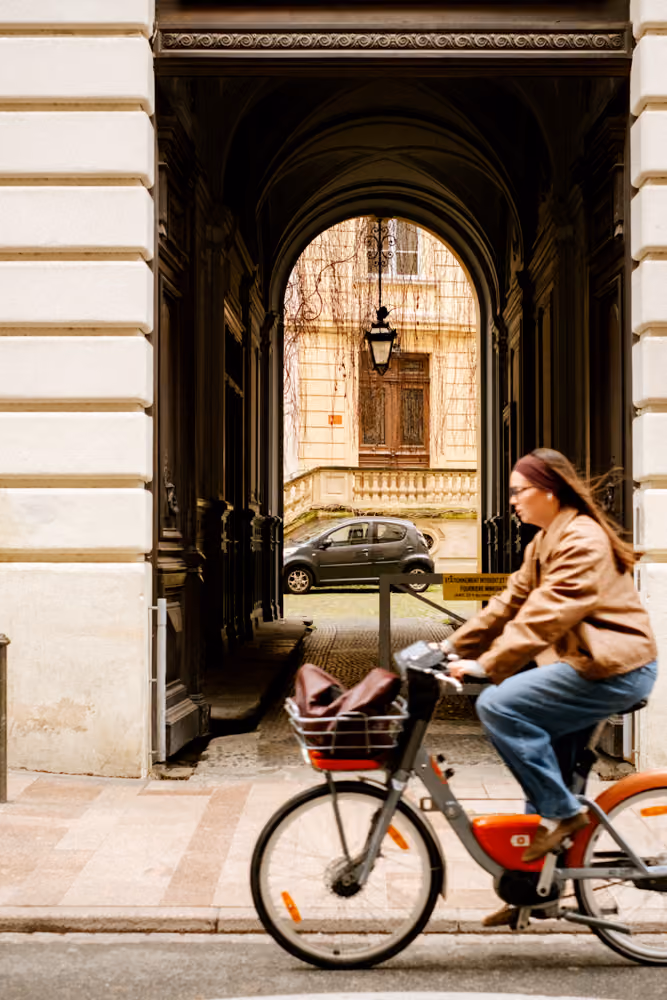 Voyageuse à vélo explorant un quartier touristique à Toulouse près d'un hébergement Glint, idéal pour un city break.