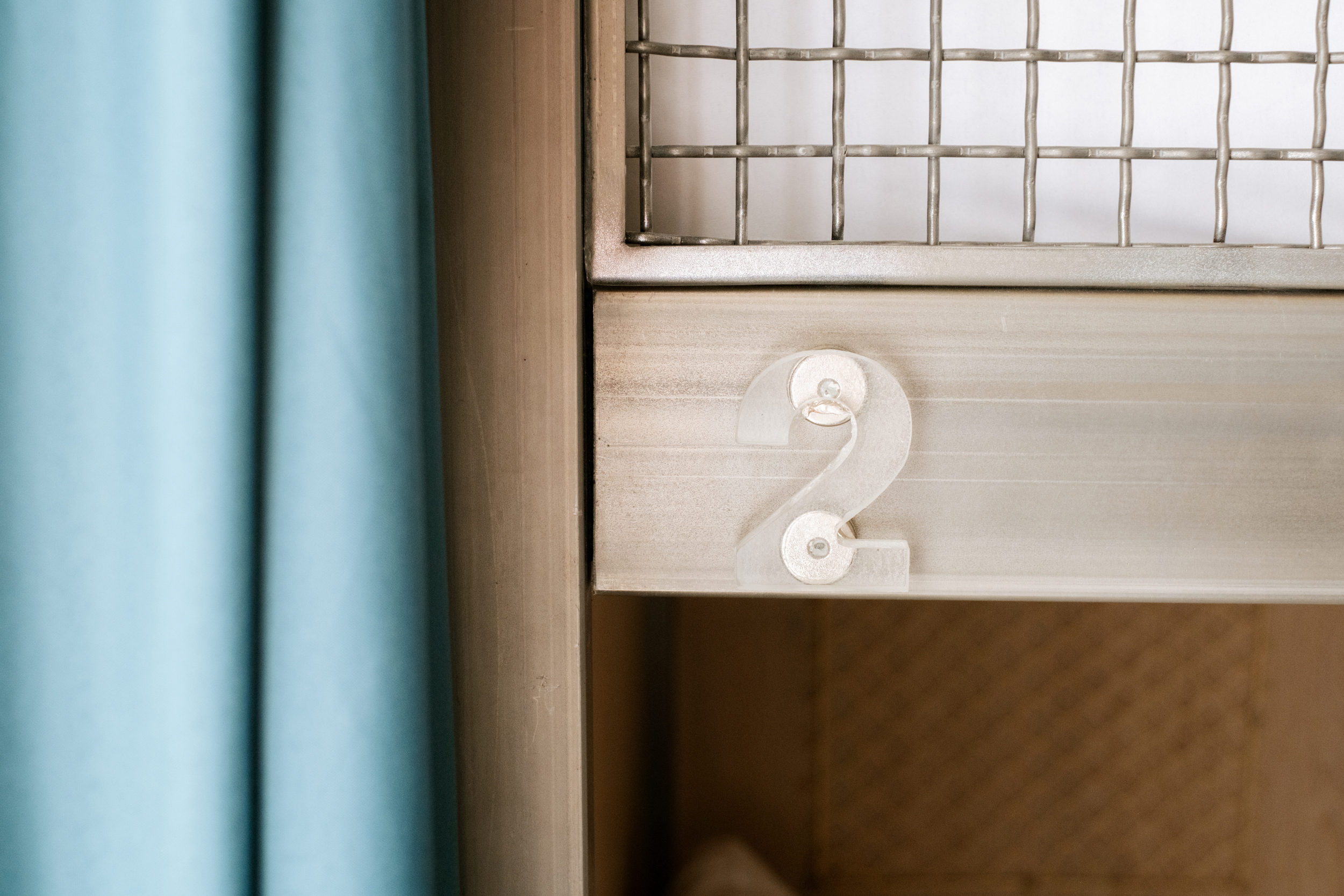 Partie supérieure d'un lit superposé en métal beige avec un numéro 2 en plastique transparent.