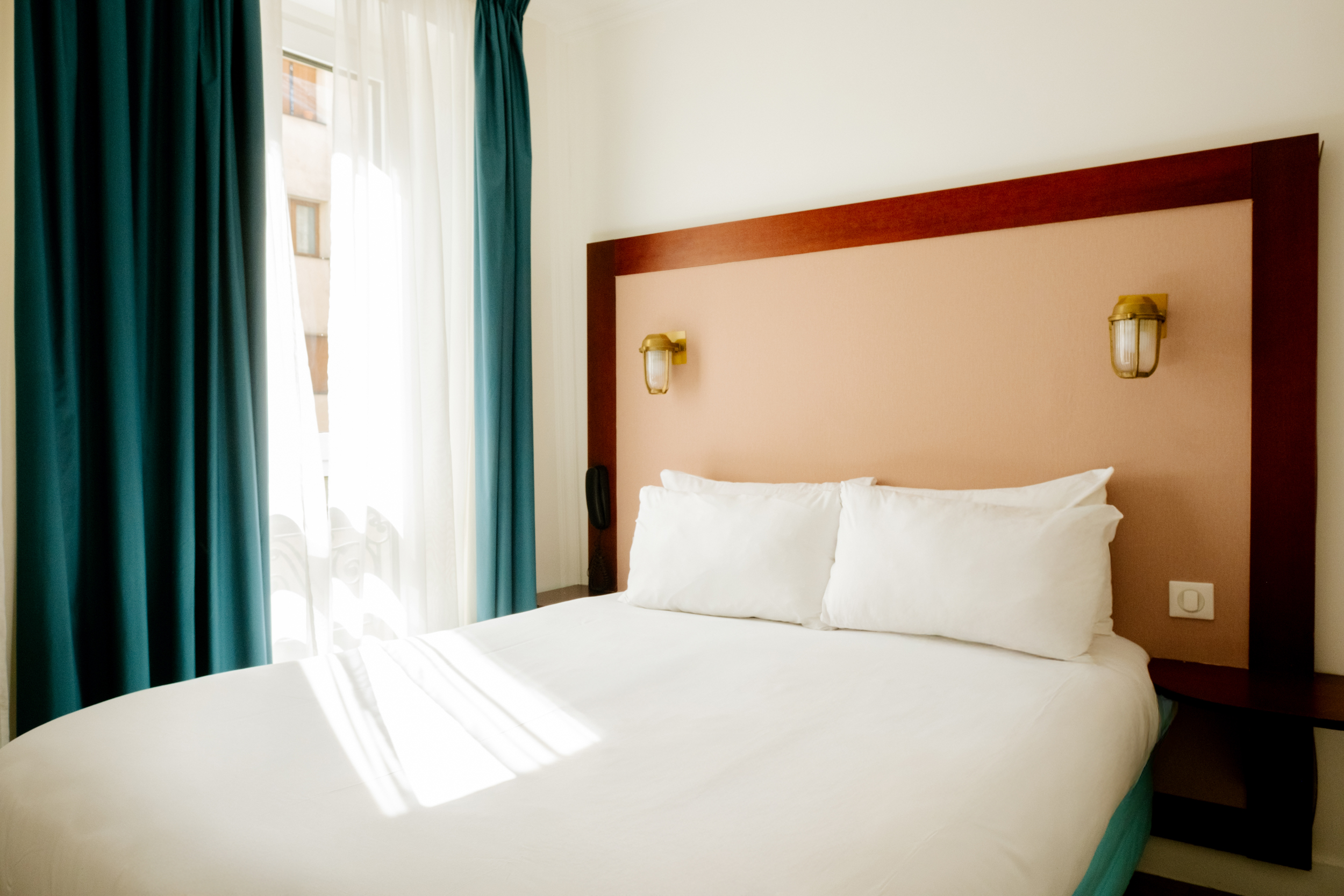 Chambre moderne avec plafond coloré et vue urbaine dans un hotel au centre-ville, géré par Glint.