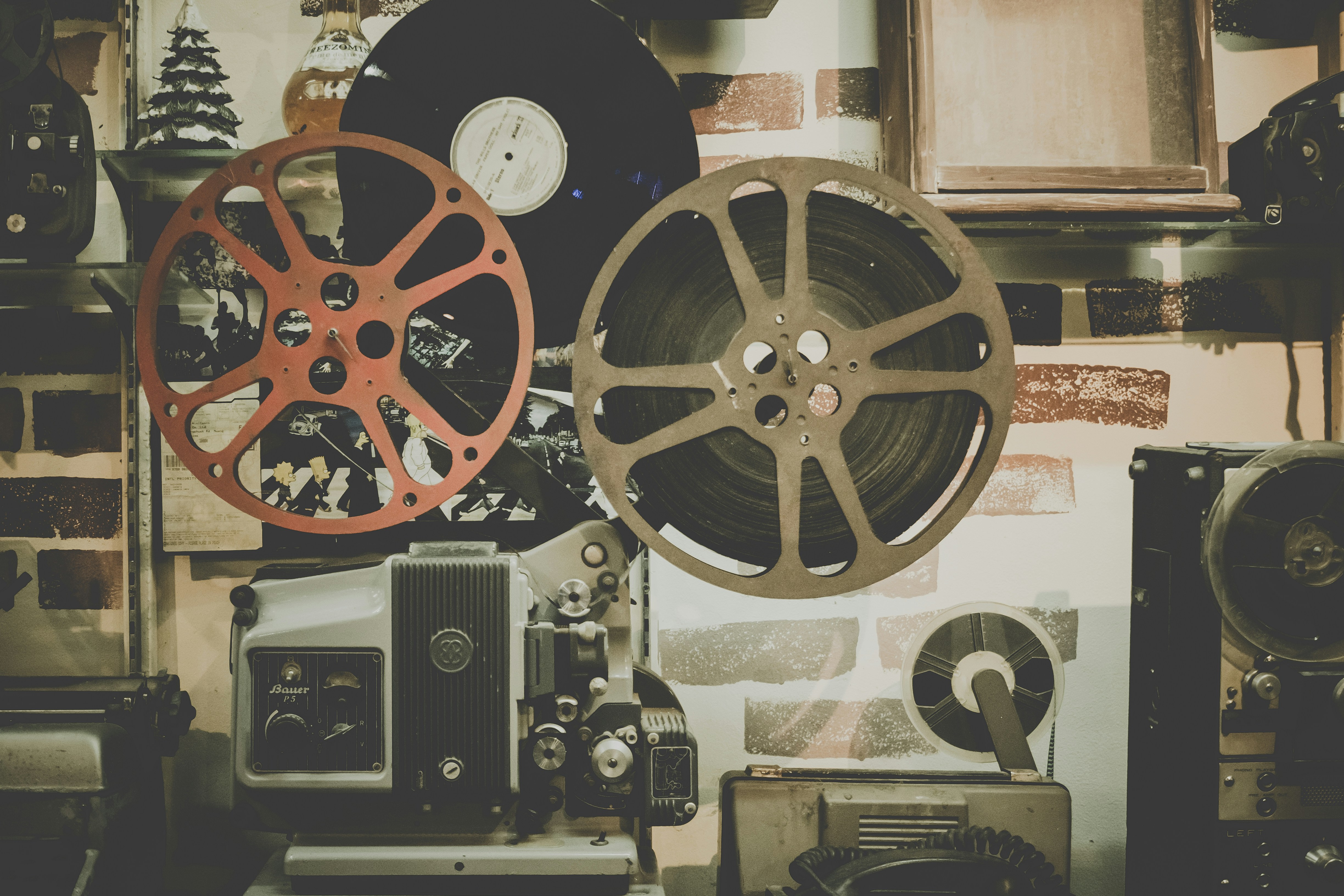 Projecteur de film vintage avec bobines et vinyle sur fond de mur en briques peintes.