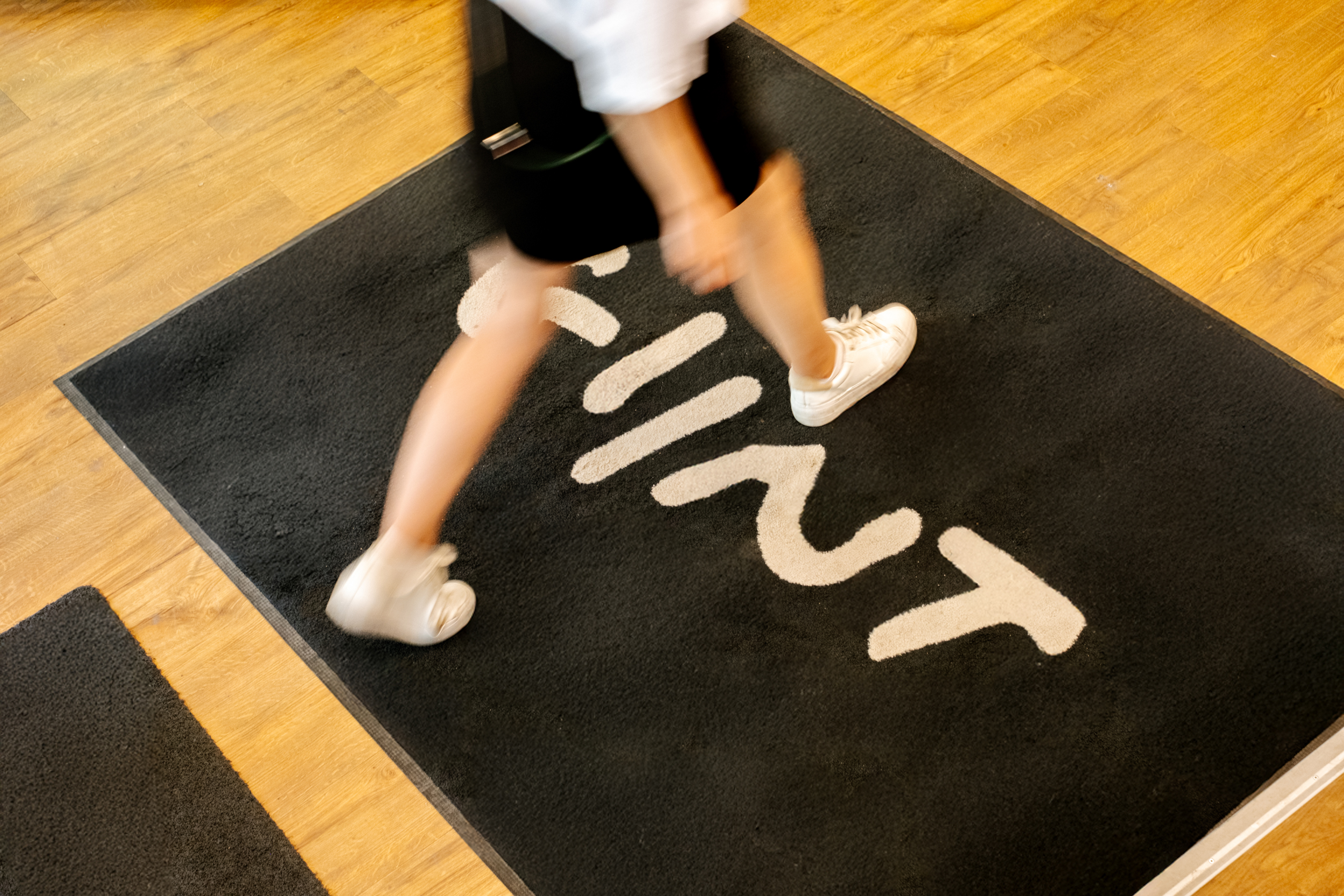Personne marche rapidement sur un tapis noir avec le mot Glint écrit dessus en blanc.
