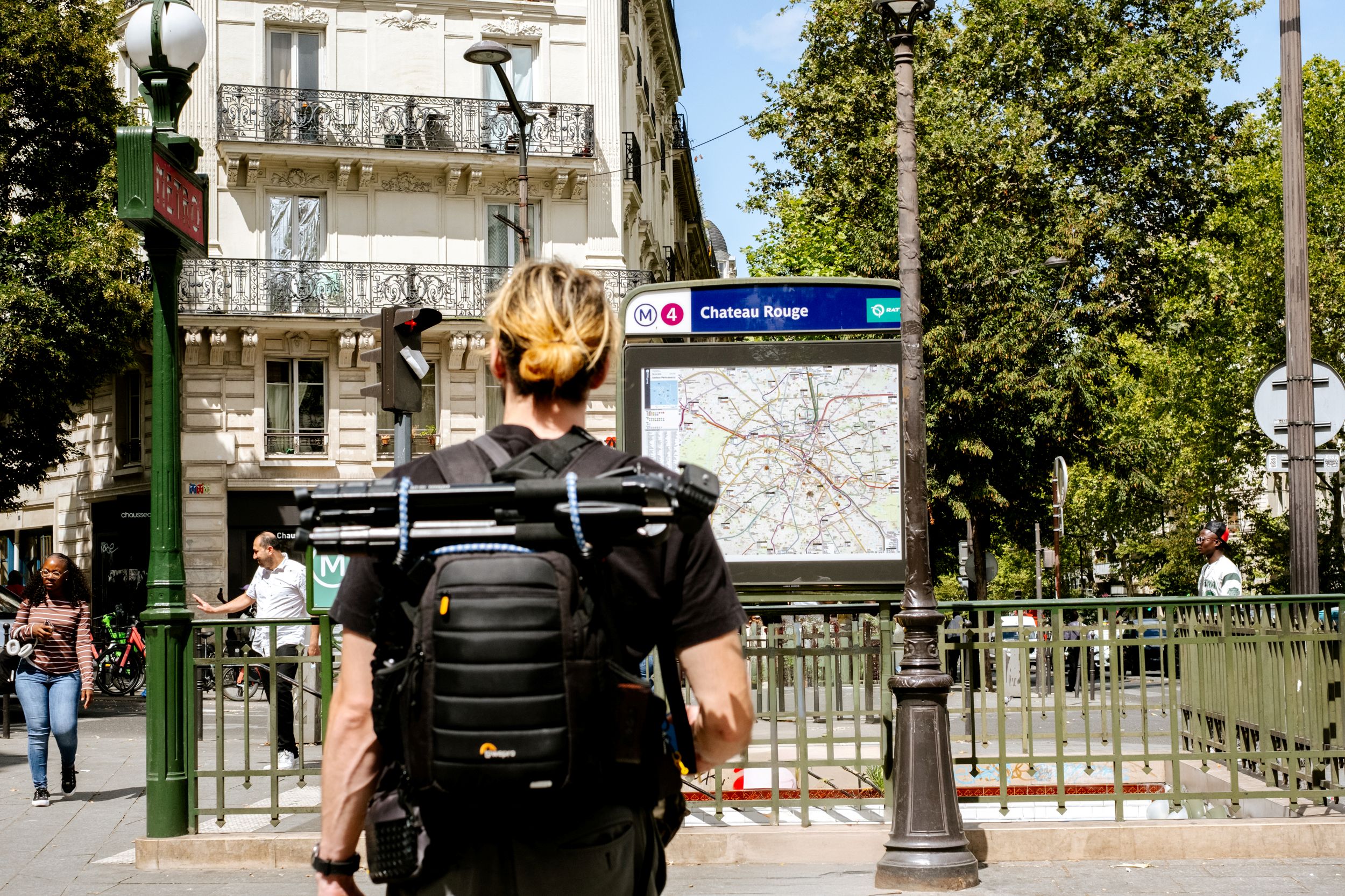 Person with camera gear backpack looking at Paris Metro line 4 station map at Chateau Rouge.