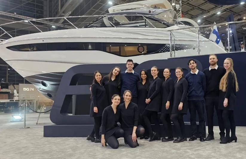 Das eventas-Team in dunkler Uniform vor einer Yacht am Princess-Yachts-Stand auf der BOOT Düsseldorf