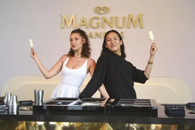 Zwei Promoterinnen halten Magnum-Eis hoch, hinter dem Stand der goldene Magnum-Schriftzug