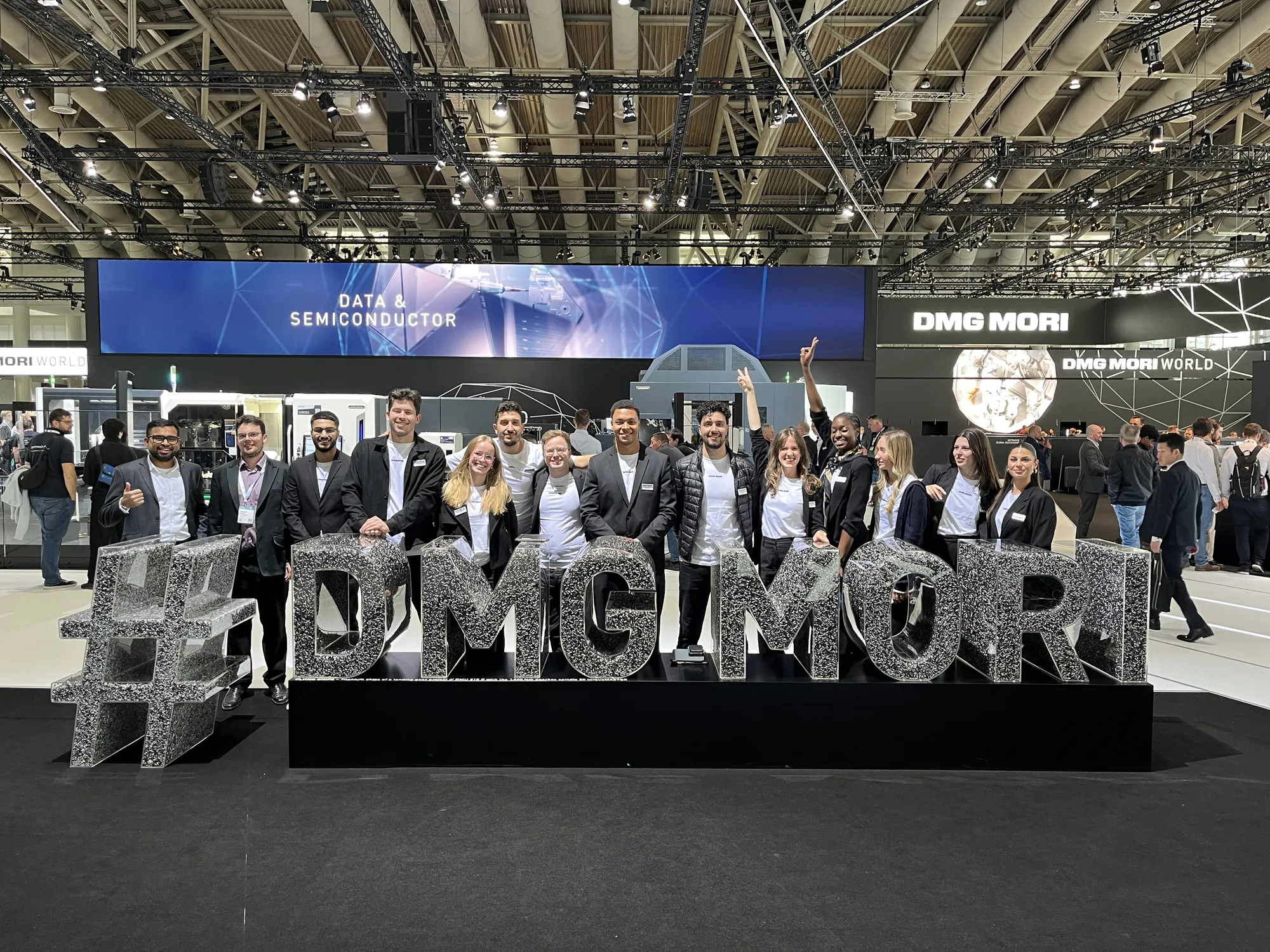 The eventas team in black blazers in front of the #DMG MORI lettering at the DMG MORI stand at EMO Hannover 2025 | eventas