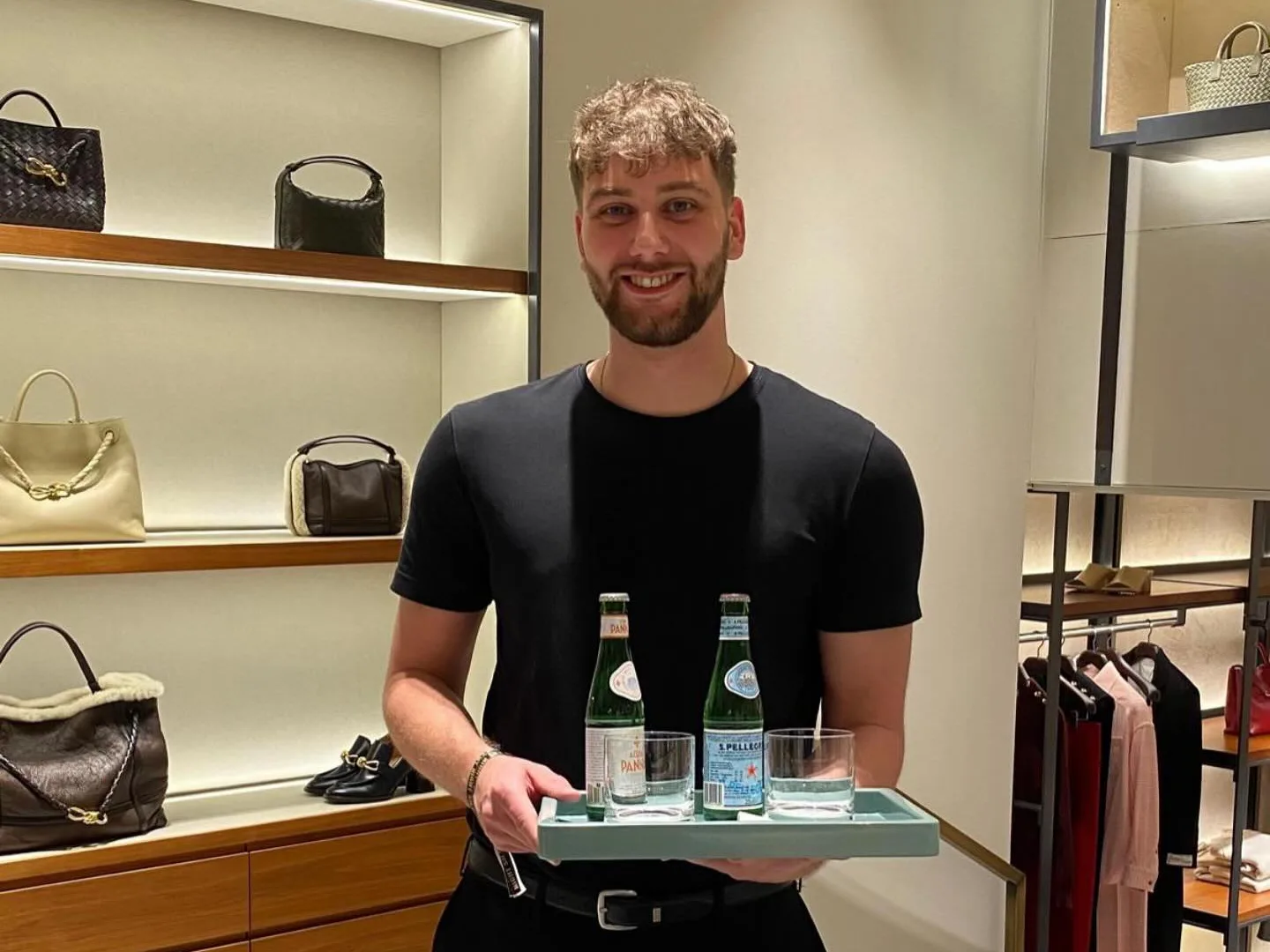 Host von eventas in schwarzer Kleidung serviert Wasser auf einem Tablett bei einem Event von Bottega Veneta | eventas