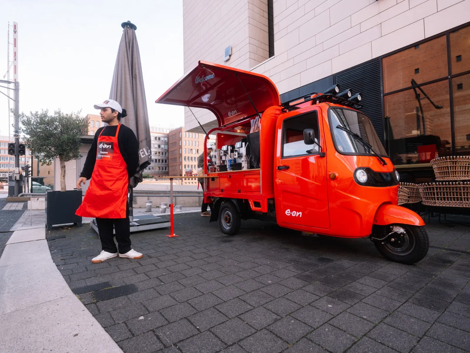 E.ON Kaffee-Ape mit Barista in roter E.ON-Schürze vor der Elbphilharmonie Hamburg bei der NeX26